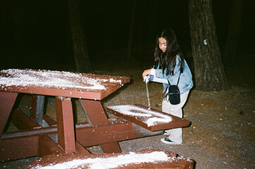 Girl Spreading Artificial Snow On A Wooden Picnic Table