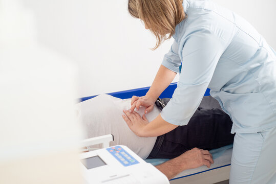 Faceless doctor palpating patient's abdomen in hospital