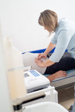 Faceless doctor palpating patient's abdomen in hospital
