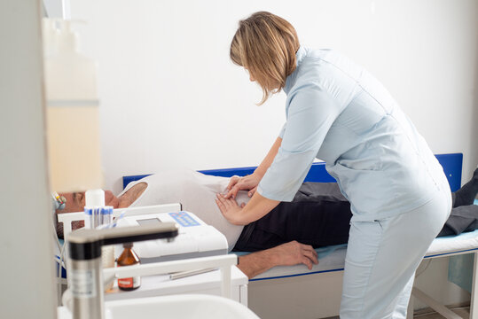 Faceless doctor palpating patient's abdomen in hospital