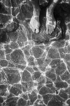 Bare feet underwater in the sunshine on the beach