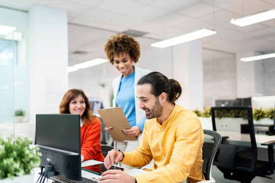 Business team collaborating on computer project in modern office