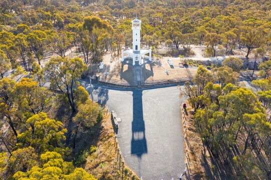 Long shadow cast by a lookout monument in a forst of gum trees