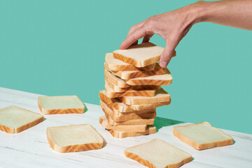 man puts a slice of sandwich bread on top of a stack