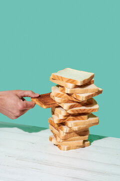 man taking a toast from of pile of untoasted slices of bread