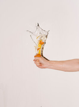 Hand Squeezing Egg with Splash Effect Against White Background