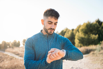 Sportsman checking time on smartwatch during training outdoors