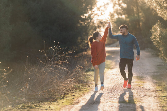 Happy couple giving high five while walking in nature during sunset