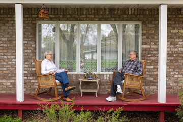 Elderly couple talking on porch in rocking chairs
