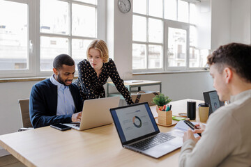 Marketing team analyzing data on laptops in modern office