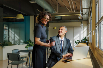 Formal business colleagues collaborating on laptop in modern office
