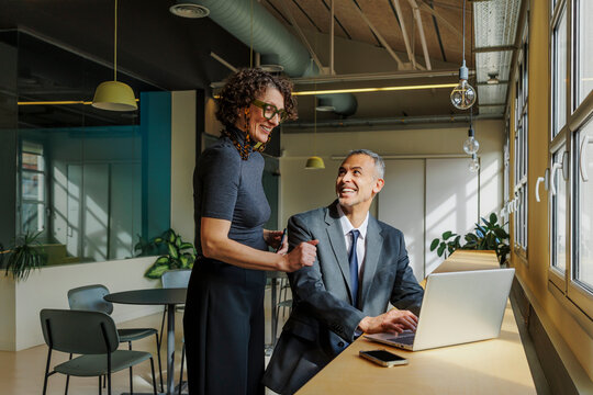 Formal business colleagues collaborating on laptop in modern office