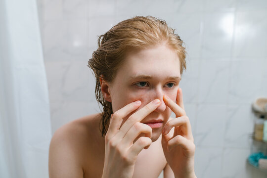 Person Examining Skin in Bathroom