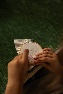 Children's hands stitch their first embroidery.