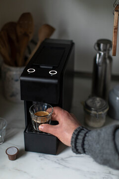 Man takes cup of freshly made espresso from coffee pod machine