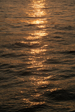 Dark brown rippled sea water surface ans sun reflection