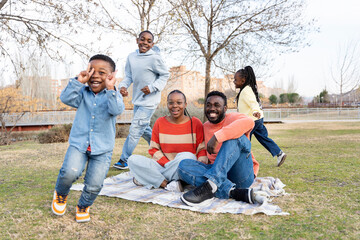 Happy family enjoying picnic in park with children playing