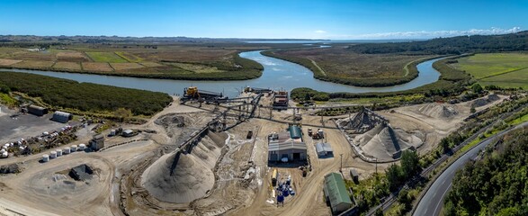 Aerial view of a sand and gravel quarry in New Zealand. Barges are loaded with materials for transport. The quarry provides resources for construction. MT REX SHIPPING, HELENSVILLE, NZ