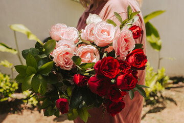 Florist holds a bouquet of a mix of red, white and pink roses