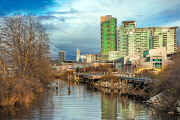 Residential area on the bank of a small river in New Westminster City, a group of apartment buildings against a cloudy dramatic sky