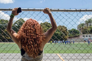 Soccer mom enthusiastically supporting her child's team from the sidelines
