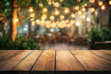 Empty wooden table outdoors at night with warm lighting.  Bokeh background of patio seating area