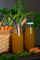 Healthy eating. Two bottles of fresh carrot juice on the table against the background of a wicker basket with carrots.