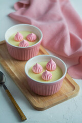 Cream dessert in colored cups on a wooden stand with colored napkins.