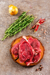 Raw meat with herbs and spices ready for cooking are on wooden table