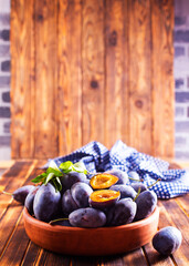 Fresh plums on plate over dark wooden background