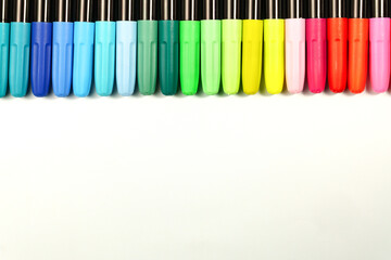 colored markers placed in a row on a white background with copy space