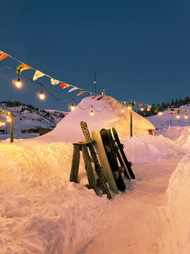 Snowy base camp with yurts, decorated with flags and cozy lights
