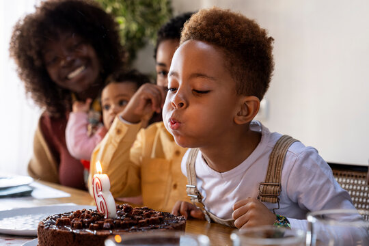 Kid blowing birthday cake candle during bday celebration 