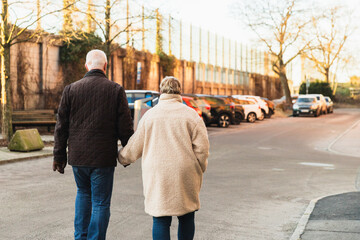 Senior couple holding hands walking down the street