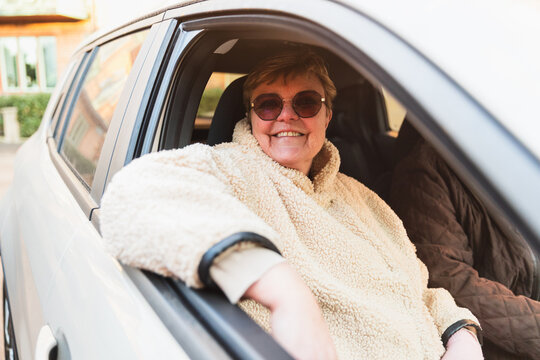 Senior woman sitting in car enjoying afternoon sunlight