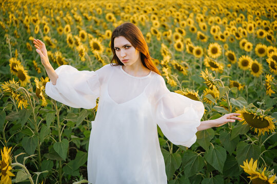 A girl in white in a sunflower field at sunset