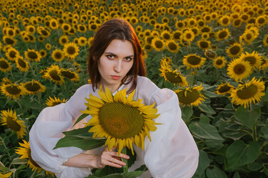 A girl in a field holding a sunflower