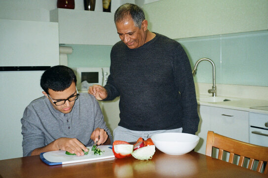 Cooking Together. A Father Teaches His Teen Son to Chop Vegetables