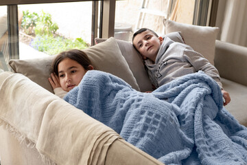 Cozy Siblings Relaxing Under a Cozy Blanket on a Cold Day