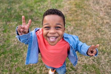 Happy child gesturing peace sign outdoors in a park
