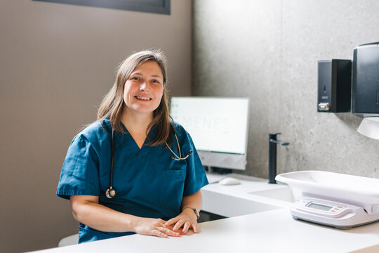 Veterinarian smiling in her modern clinic with computer and pet scale