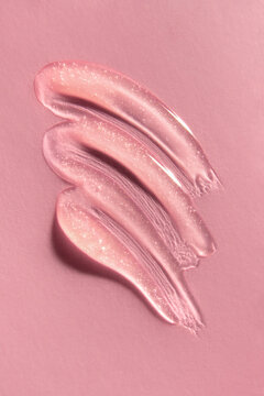Pink lip gloss swatch smeared on paper background. 