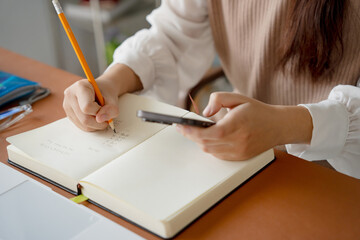 Asian girl student doing exam hand holding pencil writing answer in university classroom education...