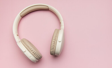 Modern wireless headphones lying on pink background
