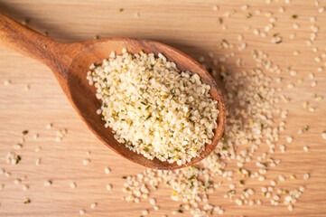 Peeled hemp seeds in wooden spoon on wooden table close-up, top view. Superfood, healthy tasty...