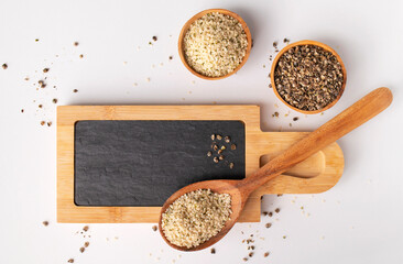 Hemp seeds in wooden spoon and bowls, kitchen writing board on light background, top view....