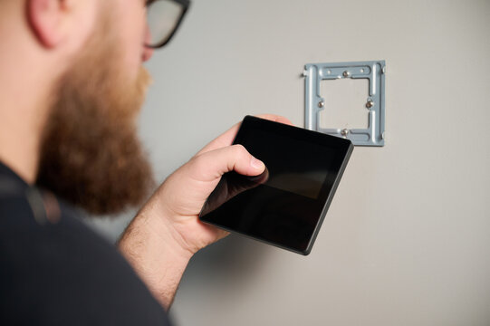 Security alarm installation. Security technician installing safe monitor on wall in the new office. Installing security system. Man worker installing alarm technology insurance in home