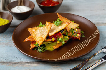 Nachos chips with sauces on a porcelain plate