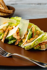 Chicken Caesar salad served on a porcelain plate with crusty bread