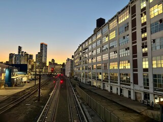 Naklejka premium City skyline and train tracks at sunset with industrial buildings